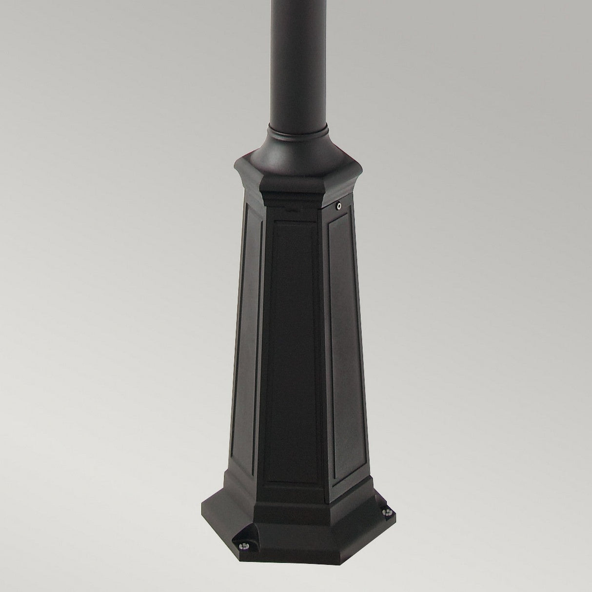 The Valencia 2 Light Twin Head Lamp Post in black showcases a close-up of its base, ideal for enhancing garden pathways. The base features a square, ornate design with four visible screw holes at the corners and is set against a simple gray background.