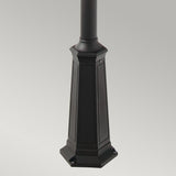 The Valencia 2 Light Twin Head Lamp Post in black showcases a close-up of its base, ideal for enhancing garden pathways. The base features a square, ornate design with four visible screw holes at the corners and is set against a simple gray background.