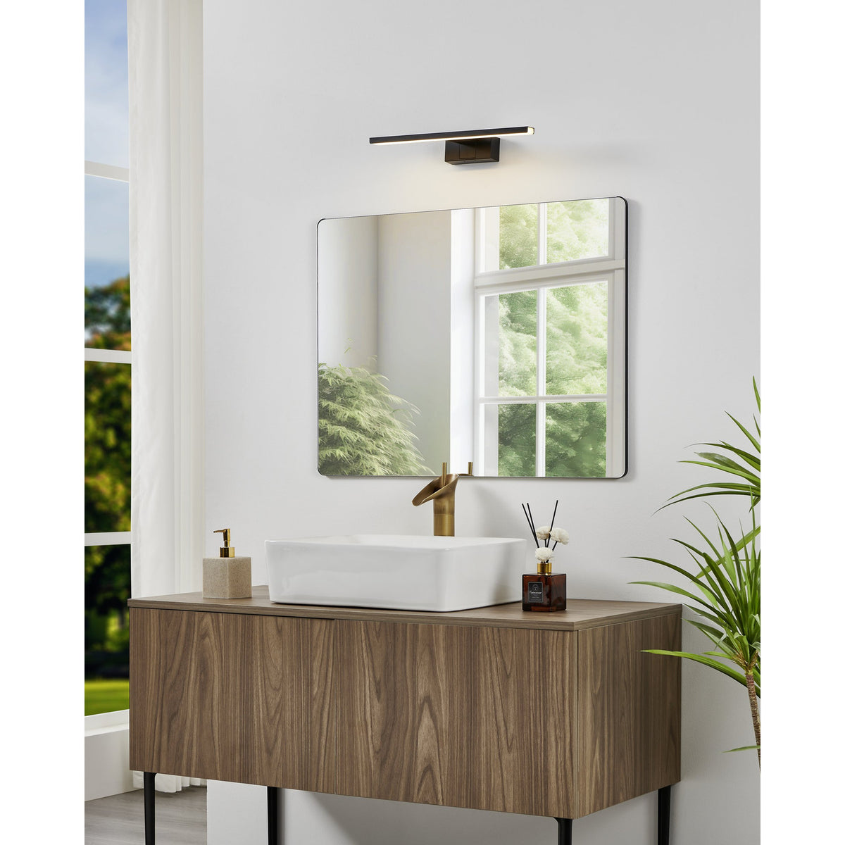 Varette LED Bathroom Mirror Light 40cm in black, mounted above a rectangular mirror in a bathroom with a wood-toned vanity, white basin, and brass tap.