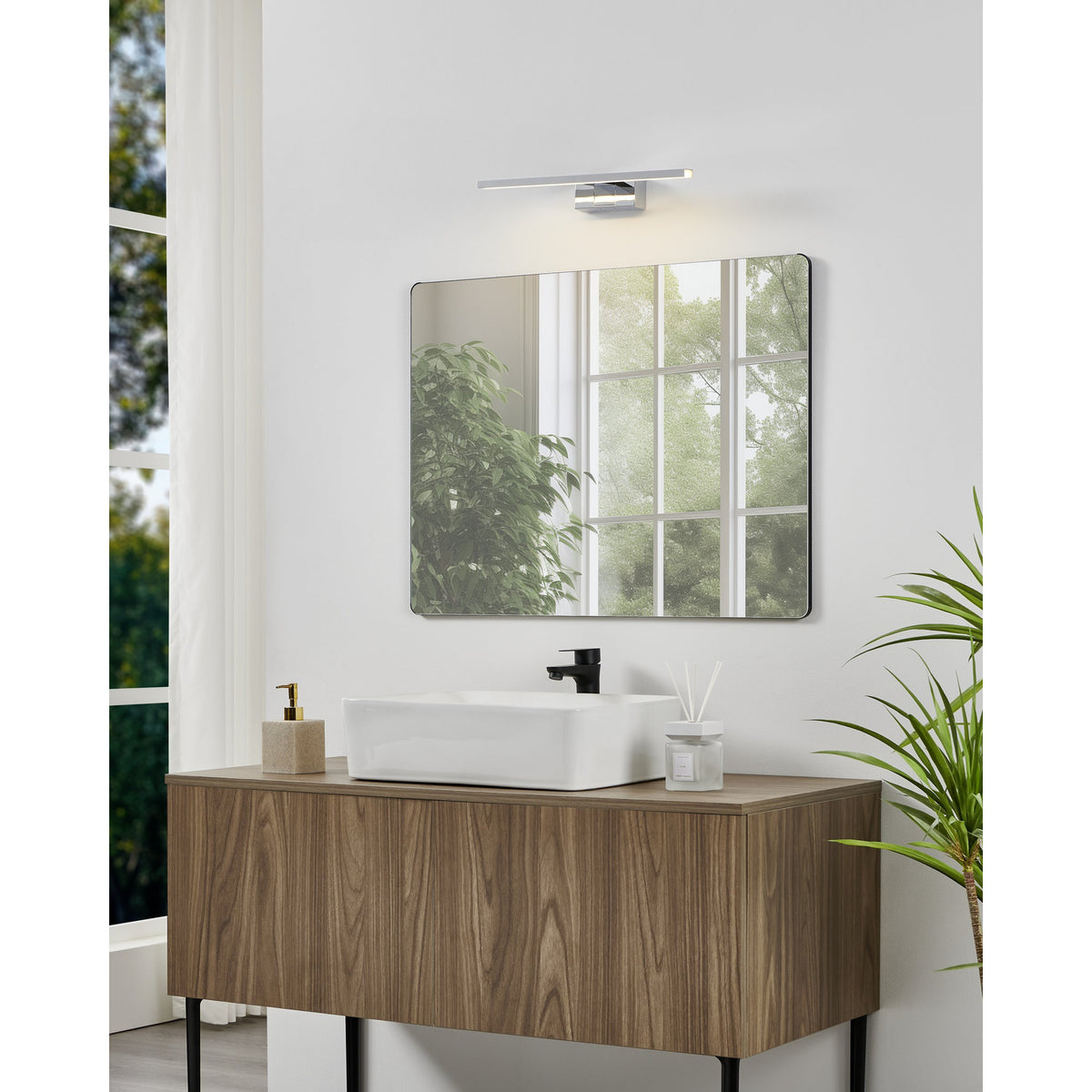Varette LED Bathroom Mirror Light 40cm in chrome, mounted above a square mirror on a bathroom vanity with wood cabinetry, white sink, and black tap.