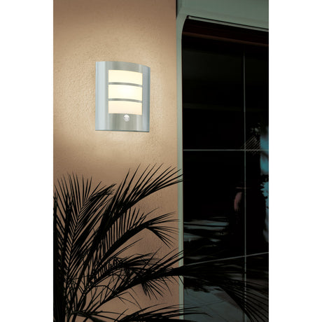 Velbessa stainless steel outdoor wall light with motion sensor, curved plate with three illuminated white panels, mounted beside a door on an exterior wall.