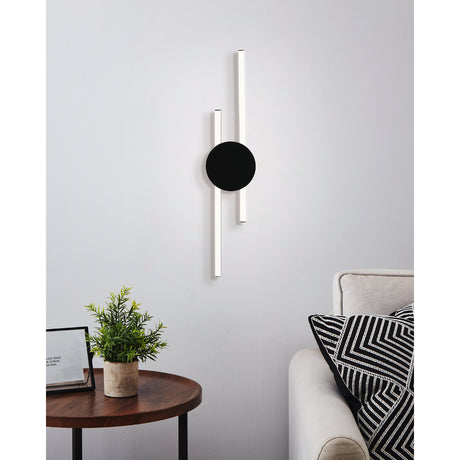 Venticello LED Flush Ceiling Light in black, shown on a living room wall with two offset vertical light bars and a round disc canopy, styled near a sofa and side table.