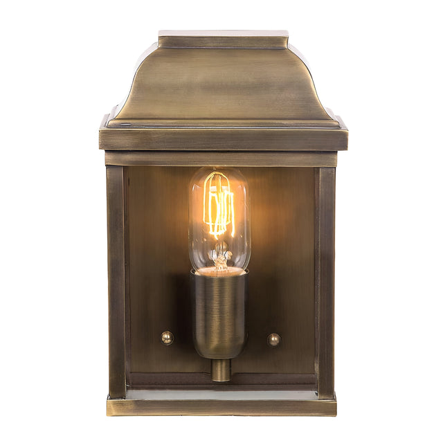 The aged brass of the Victoria 1 Light Outdoor Wall Light amplifies its vintage charm, featuring an exposed filament bulb that emits a warm glow. Its square form and decorative top exude a classic, antique style suitable for any setting. With an IP44 rating, it is ideal for outdoor use thanks to its weather resistance.