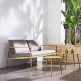Vint Aluminium 2 Seater Garden Sofa with an open-arm yellow-finished frame and grey cushions, shown indoors beside matching round side tables and a potted plant.