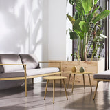 Vint Ø60cm round aluminium garden side table in mustard yellow with tapered legs, shown beside a grey sofa with two small vases on top.