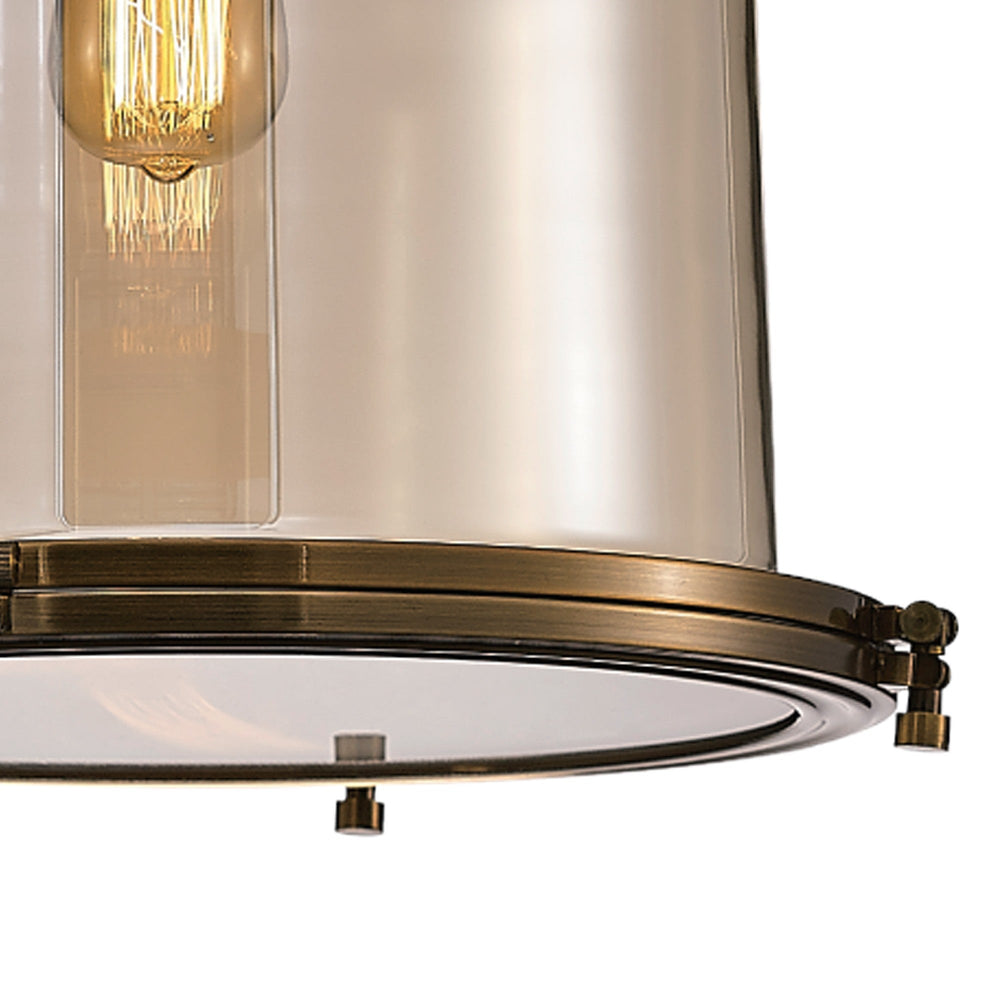 Close-up of the Vintage 33cm Bell pendant light showing the antique brass hinged base frame, riveted fittings and amber glass shade with lit E27 bulb.