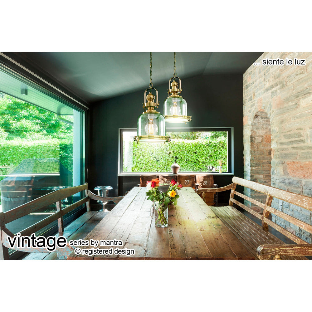 Two Vintage 33cm Bell glass pendant lights in antique brass hang above a rustic wooden dining table in a stone and dark green room.