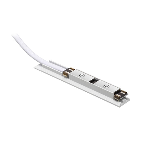Viora Magnetic Track Power Feed in white, a slim track accessory with metal contact plates and screws, white cable exiting one end, shown on a plain background.