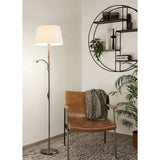 Vorbine mother and child floor lamp in satin nickel with a white tapered fabric shade and a smaller globe reading light on a gooseneck arm, shown beside a leather armchair in a living room.