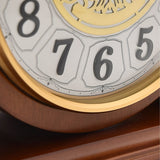 Close-up of the Westminster Barrel Mantel Clock in walnut, showing black Arabic numerals 5, 6, 7 and 8 in outlined panels with a gold-coloured bezel and filigree centre detail.