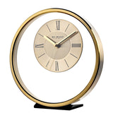 Round gold metal mantel clock with an open ring design, two-tone dial, black Roman numerals, baton markers, and slim gold hands on a black base, plain white background.
