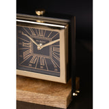 Close-up of the Square Roman Numeral Mantel Clock with a black dial, gold Roman numerals, minute track, and gold hands set in a polished gold case on a wooden stand.