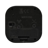 Rear view of the rounded square black metal alarm clock showing on/off switch, alarm set and time adjustment wheels, speaker holes, and battery compartment on a white background.