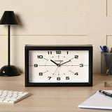 Modern rectangular mantel clock, 25cm, with black frame and white dial featuring bold numerals, shown on a desk beside a lamp and keyboard.