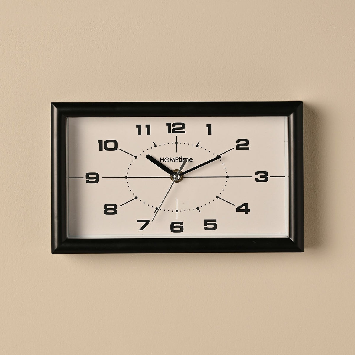 Modern rectangular mantel clock, 25cm, with a black frame and white dial featuring bold black numerals, slim black hands and a dotted oval track, shown wall-mounted against a neutral background.