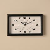 Modern rectangular mantel clock, 25cm, with a black frame and white dial featuring bold black numerals, slim black hands and a dotted oval track, shown wall-mounted against a neutral background.