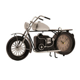Black and silver metal motorbike mantel clock with spoked front wheel, fuel tank, handlebars, and a round cream clock face set into the rear wheel, shown on a kickstand.