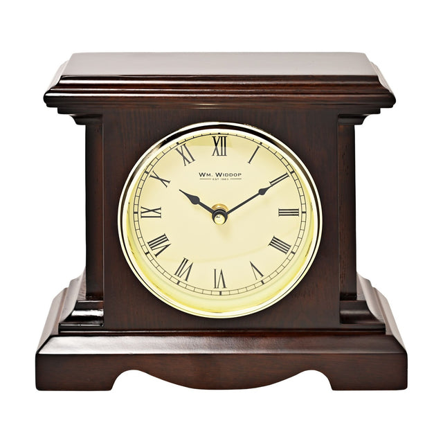 Square mantel clock in dark walnut finish with stepped moulded top and squared pillars, featuring a cream dial, black Roman numerals and gold-coloured rim, shown on a plain white background.