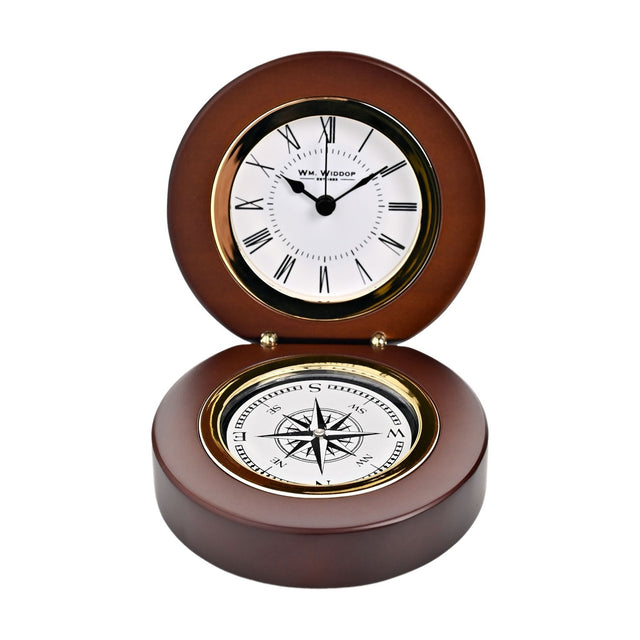 Round folding mantel clock in walnut-finish wood, open to show a white Roman numeral dial with gold-tone bezel above a compass rose set into the base, on a plain white background.