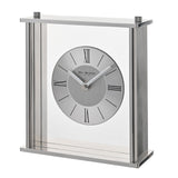 Square mantel clock with slim silver frame and clear glass panel, round two-tone silver dial with black Roman numerals and baton markers, on a plain white background.
