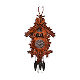 Mahogany wooden cuckoo wall clock with a carved stag's head and antlers atop a pitched roof, roundabout figures, a bird, and hanging pinecone weights, shown on a white background.