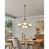 Walbane Glass 3 Light Pendant in bronze, with scrolled metal arms and upturned white satin glass shades around a central frosted glass bowl, hung above a dining table.
