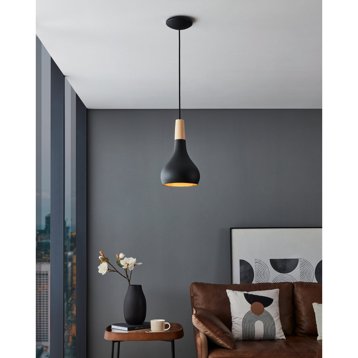 Walette Pendant Light 18cm in matt black steel with a wood collar, teardrop shade on a black cord, hanging above a side table in a grey living room.