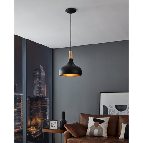Walette Pendant Light 28cm hanging above a sofa in a living room, with a black steel dome shade and light brown wood neck against a grey wall and city view.