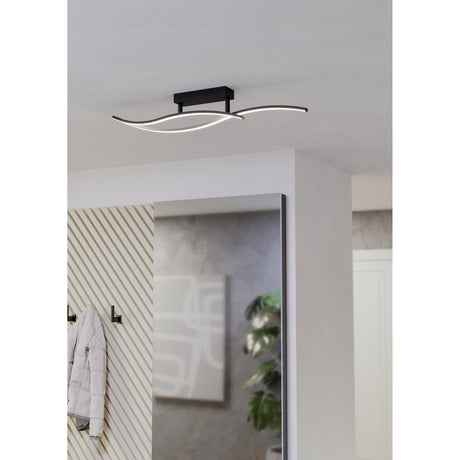 Wasmane LED flush ceiling light in black, with two crossing wave-shaped bars and integrated white diffusers, mounted on a hallway ceiling.