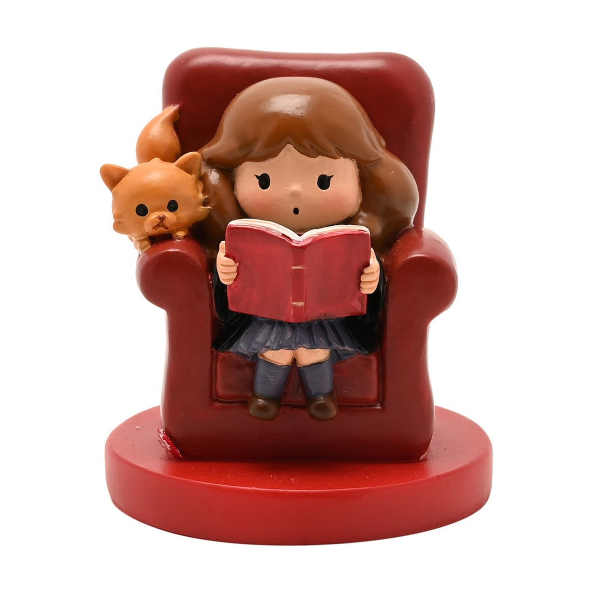 Resin figurine of Hermione reading a book in a deep red armchair with ginger cat Crookshanks beside her, on a red base against a plain white background.