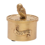 Round gold trinket box with a detailed owl figure on the lift-off lid and "HEDWIG" engraved on a scrolling banner, shown on a plain white background.