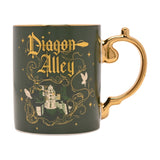 Green porcelain mug with gold handle, featuring "Diagon Alley" in gold Gothic script, scrollwork, stars, owls, and a domed building design, on a white background.