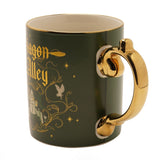 Porcelain mug in matt green with gold rim and gold handle, featuring "Diagon Alley" in gold Gothic script, owls, stars, and shopfront artwork, shown on a white background.