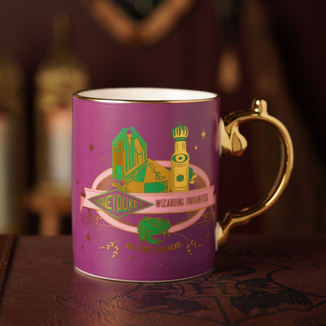 Harry Potter Honeydukes Collectable Mug 340ml in matt magenta porcelain with a gold handle, gold rim, and green sweet boxes, bottle, and frog design above "High Street, Hogsmeade" text.