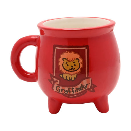 Red stoneware cauldron mug on three short feet with a cartoon lion crest and "Gryffindor" banner printed on the glossy red body, white interior, set against a plain background.