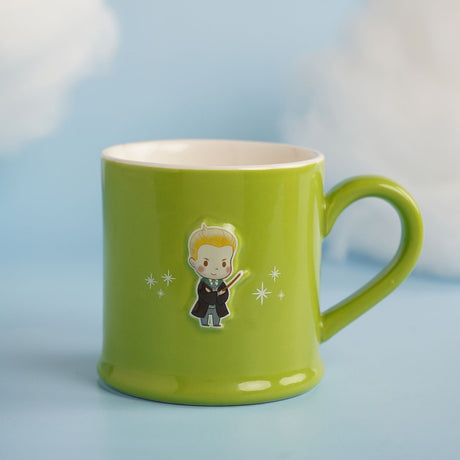 Green glossy stoneware mug with white interior, featuring an embossed cartoon Draco figure in robes holding a wand, surrounded by white star accents, set against a light blue background.
