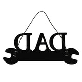 Black wooden spanner-shaped wall plaque with "DAD" cut out above a black handle, hung on a cord against a plain white background.