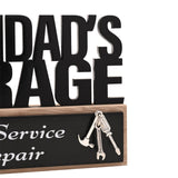 Close-up of a wooden Grandad's Garage plaque with bold black cut-out lettering, a black panel reading Quality Service and Repair, and a silver hammer, spanner and screwdriver charm.