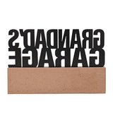 Grandad's Garage wooden standing plaque with bold black cut-out lettering on a natural wood base, shown on a plain white background.