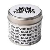 Round lidded tin scented candle in silver metal with white label printed "Mum You're The Tits" in bold black text, shown on a plain white background.
