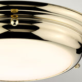 A close-up of the Welland LED Light Mini Flush in polished brass, showcasing its stylish appeal with a white glass cover. The reflective surface includes two small screws, and when turned on, it emits a warm glow. Its reliable performance is highlighted by an IP54 rating.