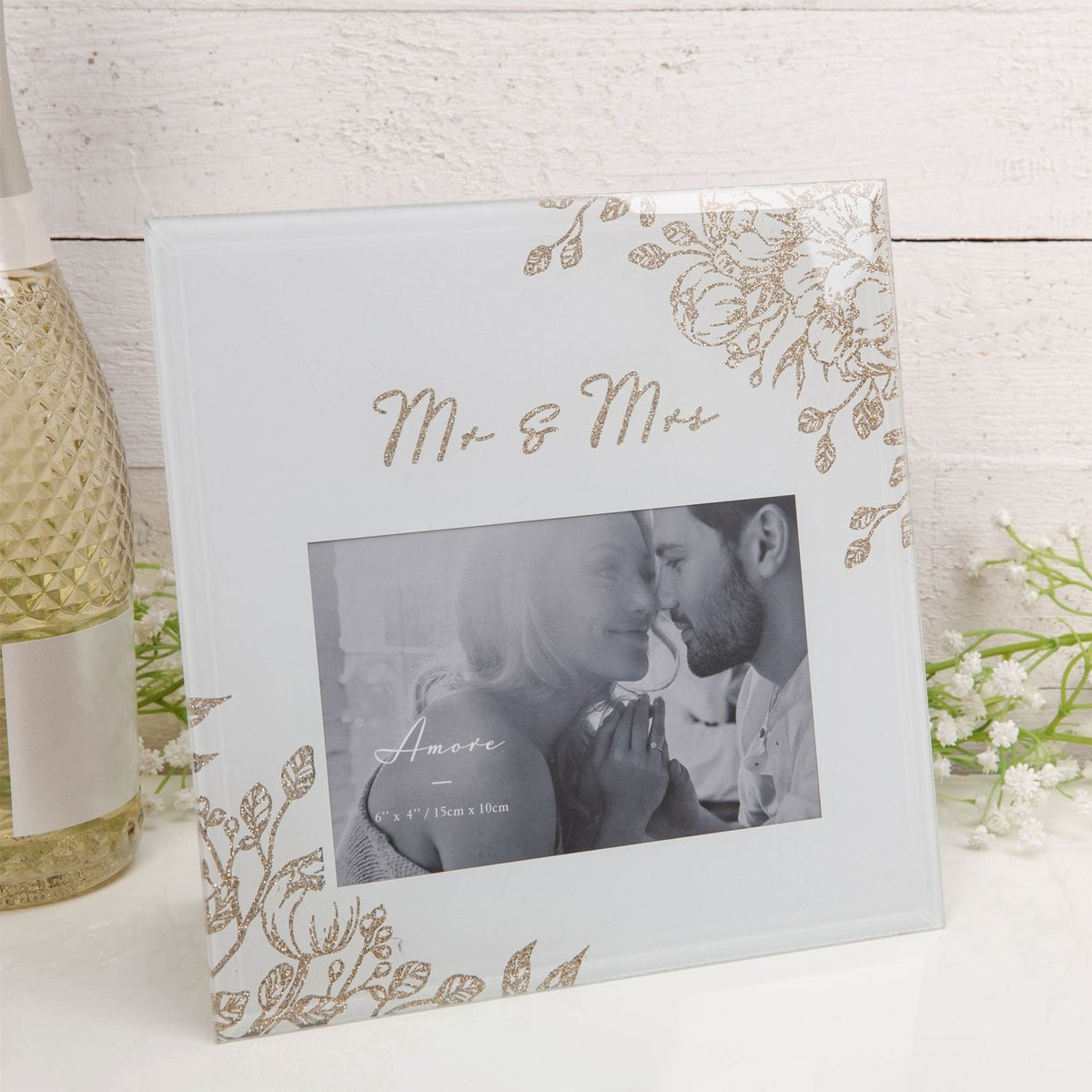 Square grey glass photo frame with gold glitter floral corners and "Mr & Mrs" script, holding a 6 x 4in landscape photo, shown against a light backdrop.