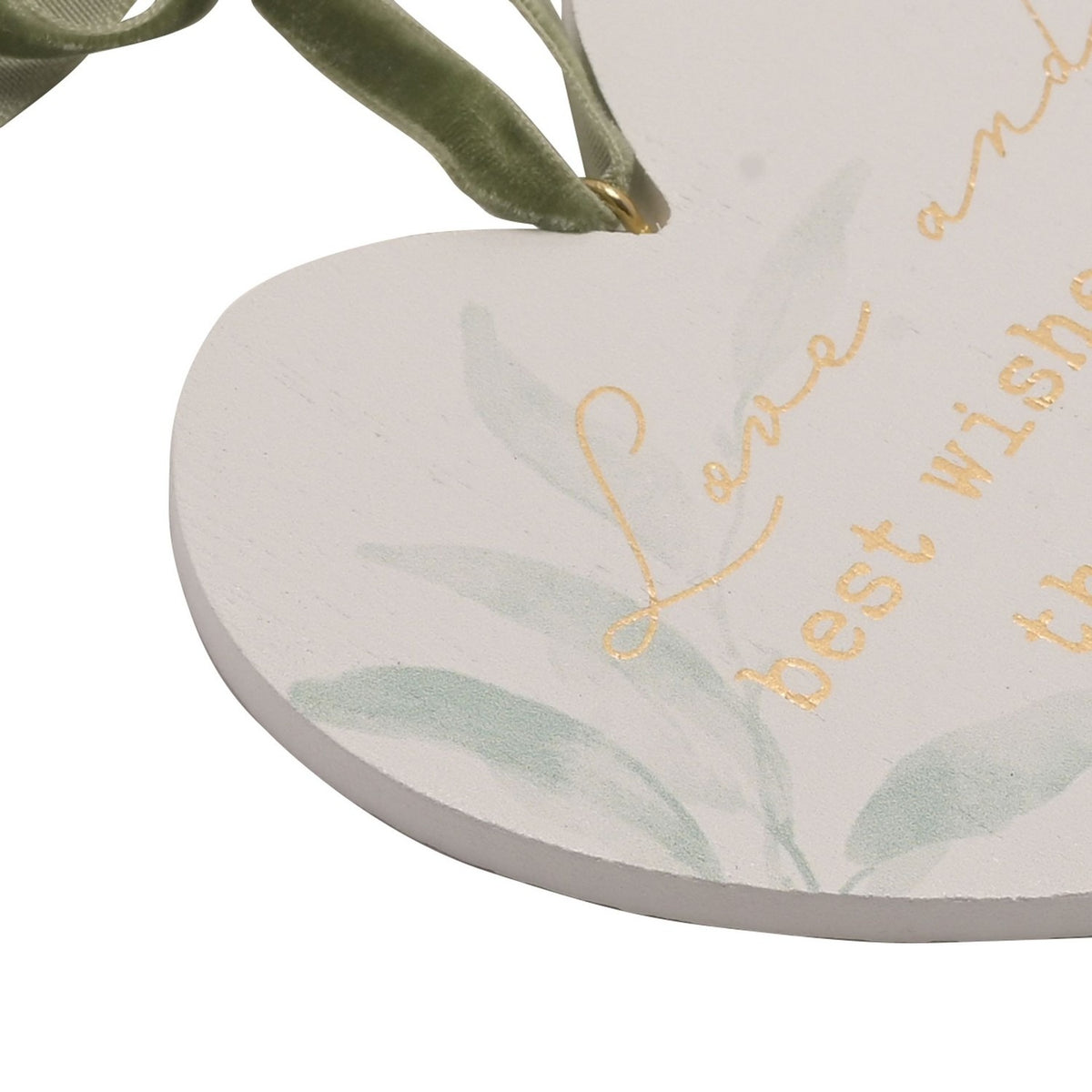 Close-up of the white heart-shaped hanging plaque with sage green foliage and gold script reading "Love and best wishes," suspended by a sage velvet ribbon.