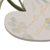 Close-up of a white hanging heart plaque with pale green leaf print and gold "Beautiful bridesmaid" lettering, hung by a green ribbon bow.