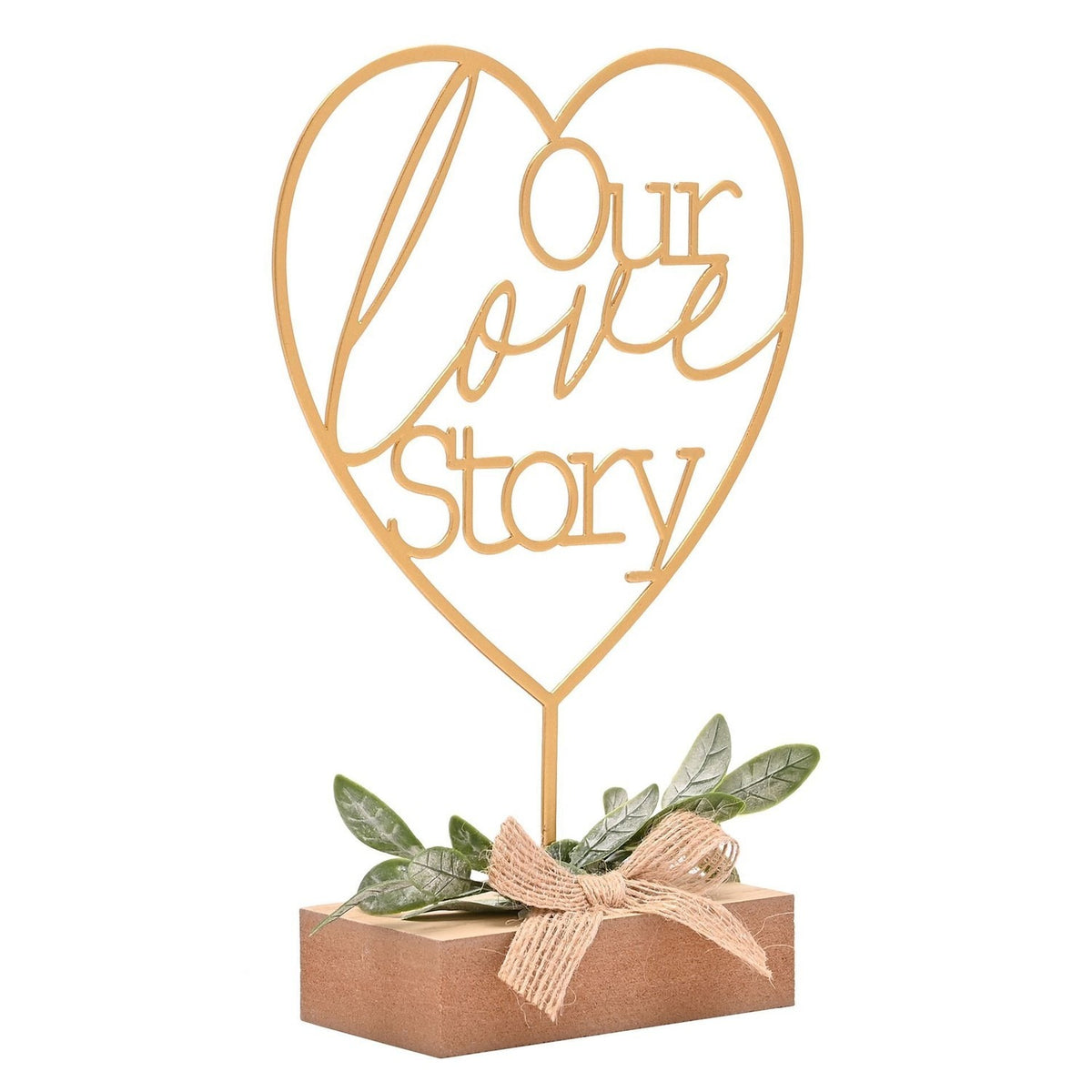 Gold metal heart mantel plaque reading "Our love Story" on a slim stem, set in a wooden block base with green leaf sprig and burlap bow, on a white background.