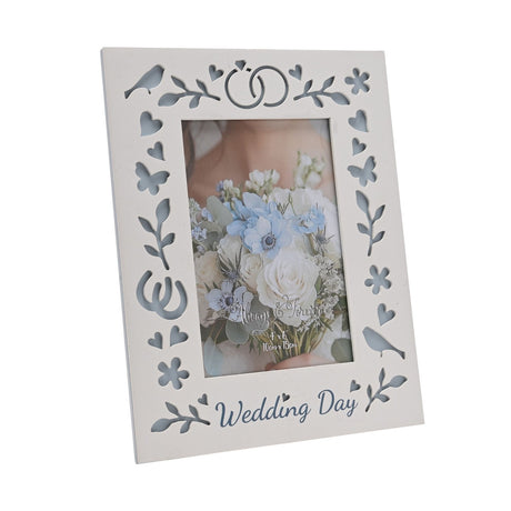 White laser cut wooden photo frame for a 6x4in portrait photo, with "Wedding Day" script, linked rings, birds, hearts and butterflies cut through to blue backing.