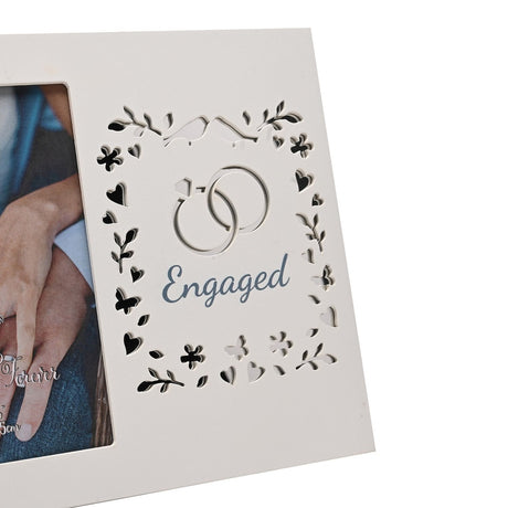 White wooden photo frame with laser cut panel showing interlinked rings, birds, hearts and leaves around "Engaged" in blue, beside a 6x4in photo opening.
