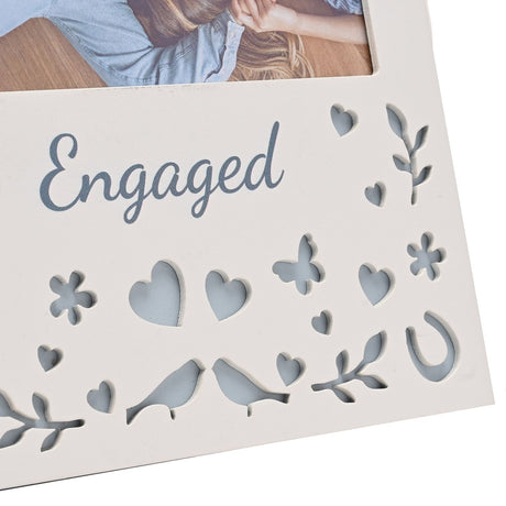 Cream wooden Engaged photo frame with 6 x 4in landscape photo window, grey-blue script text, and cut-out hearts, flowers, butterfly, birds and horseshoes below.