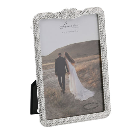 Rectangular silverplated photo frame with braided rope border and raised infinity knot at the top, holding a wedding photo, shown on a plain white background.