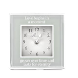Square mantel clock, 15cm, with mirrored grey border and white dial, reading "Love begins in a moment, grows over time and lasts for eternity," on a plain white background.